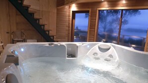 Un jacuzzi en una cabaña de madera con una escalera y ventanas amplias.