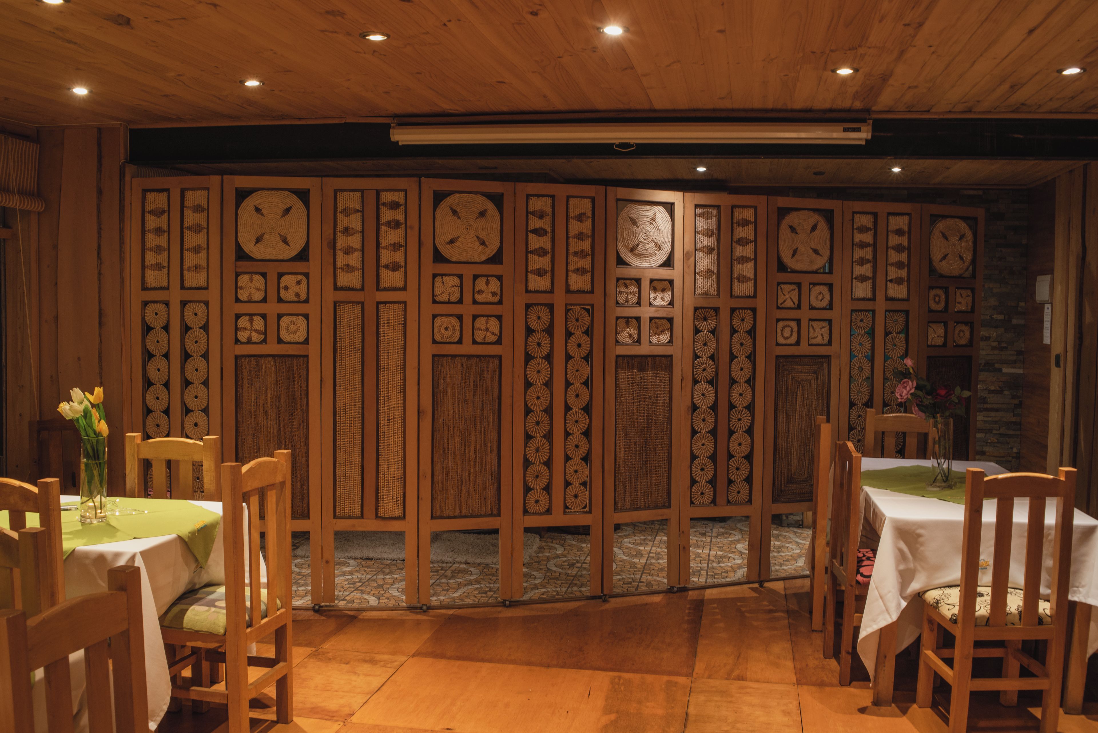 Een kamer met houten wanden met geweven patronen, een betegelde vloer en een tafel met een witte tafelkleed.