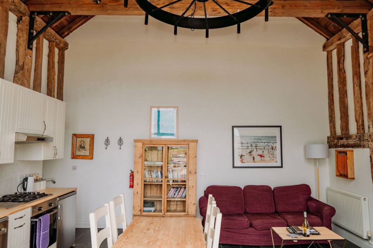A cozy kitchen with white cabinets, a wooden table, and a red sofa.