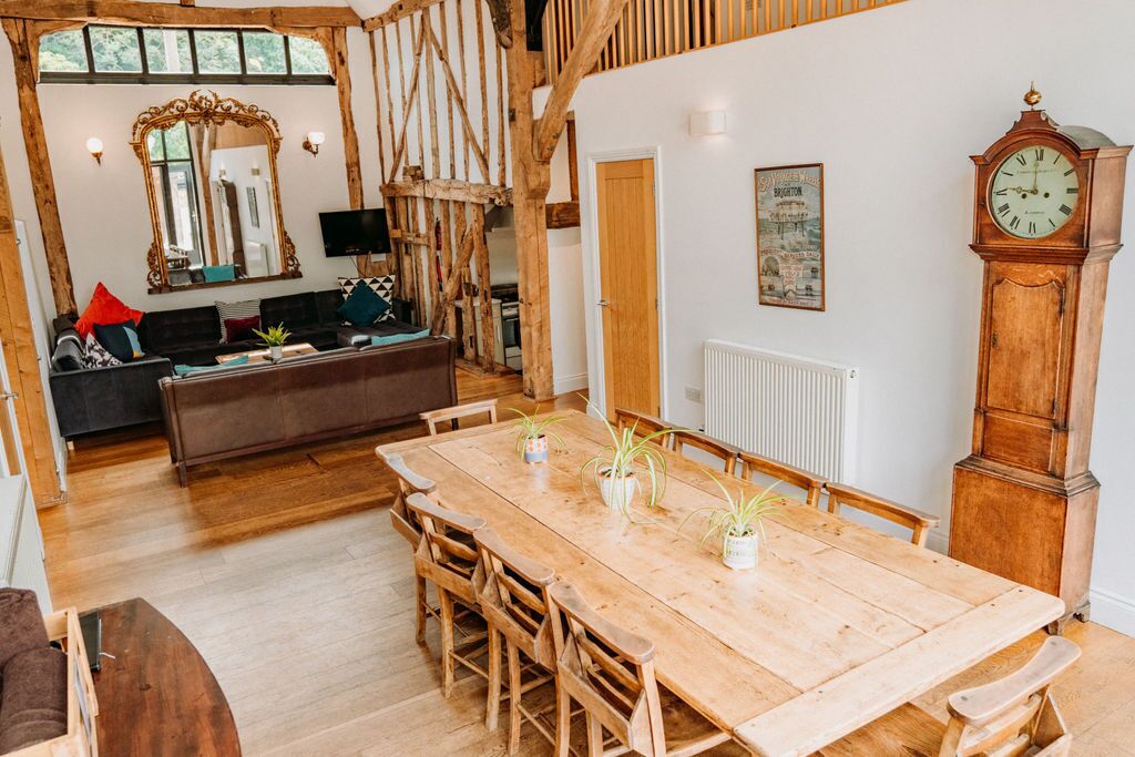 A dining area with a wooden table and chairs, a large mirror, and a vintage clock.