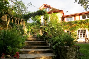 A stone staircase leading up to a house surrounded by lush greenery and ivy.
