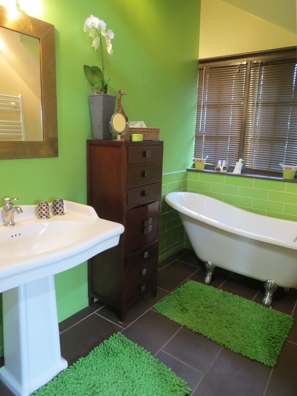 A bathroom with a white sink, a dark wooden cabinet, a white bathtub, and green tiles. - Demeure d'Hôtes L'Hermitage (Aix-les-Bains)