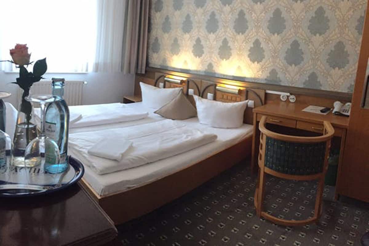 Ein Hotelzimmer mit Bett, Nachttisch und Stuhl.