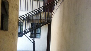 A narrow corridor with a tiled floor, a black metal staircase, and a door at the end. - Desai Villa Hotel (Nairobi)