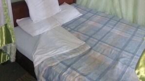 A bed with a canopy, a wooden headboard, and a checkered bedspread. - Desai Villa Hotel (Nairobi)