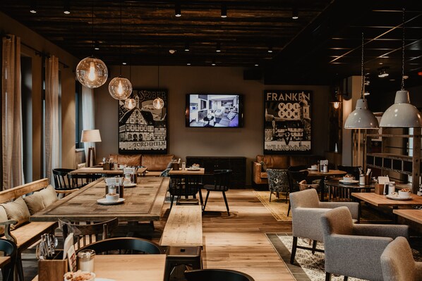 Un restaurante acogedor con mesas y sillas de madera, una pantalla de televisión y diversas decoraciones en las paredes.