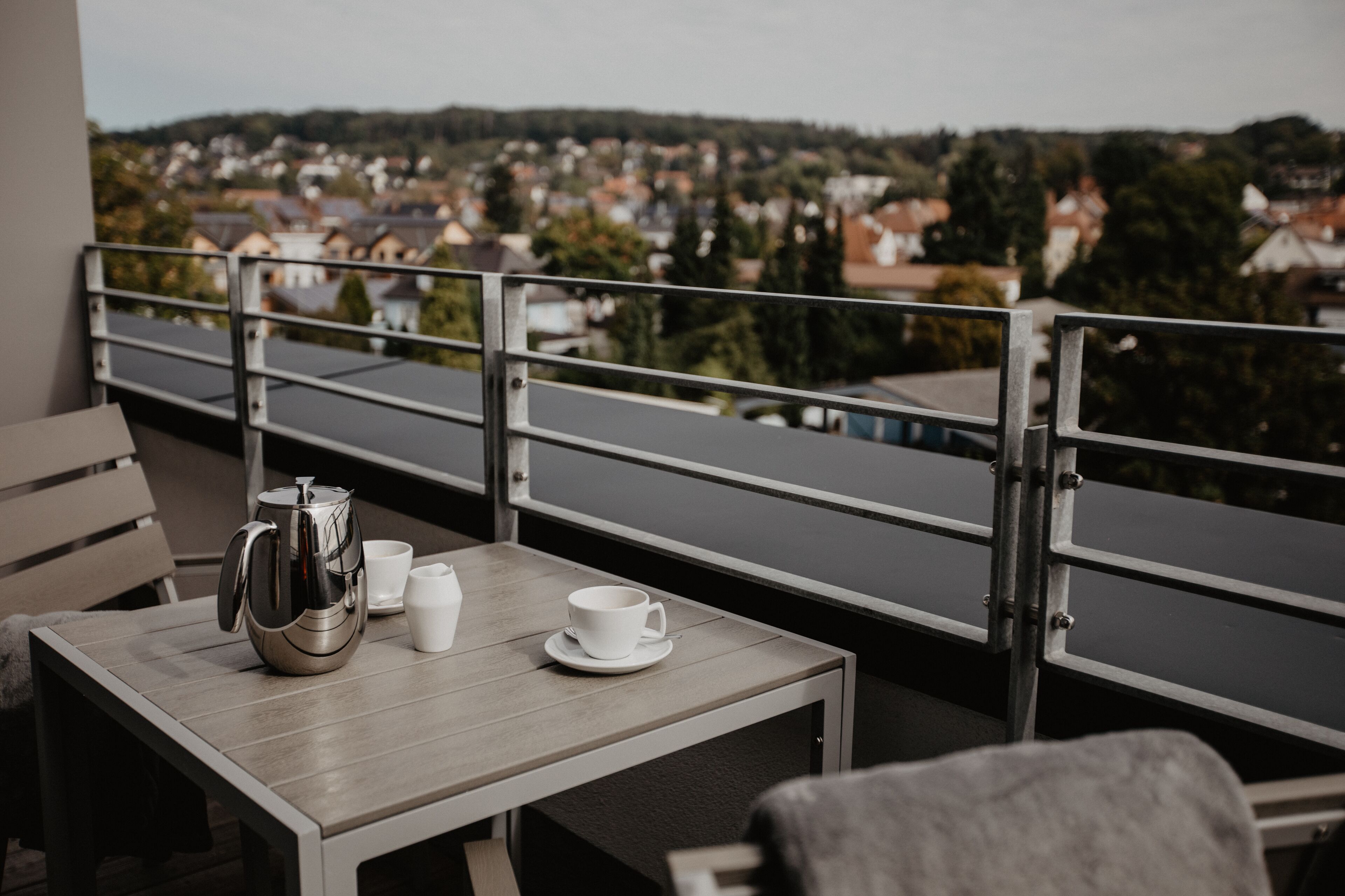 A balcony with a table, a kettle, and two cups.