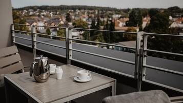 A balcony with a table, a kettle, and two cups.