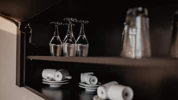 Una encimera de cocina con copas de vino, platos y una cafetera.