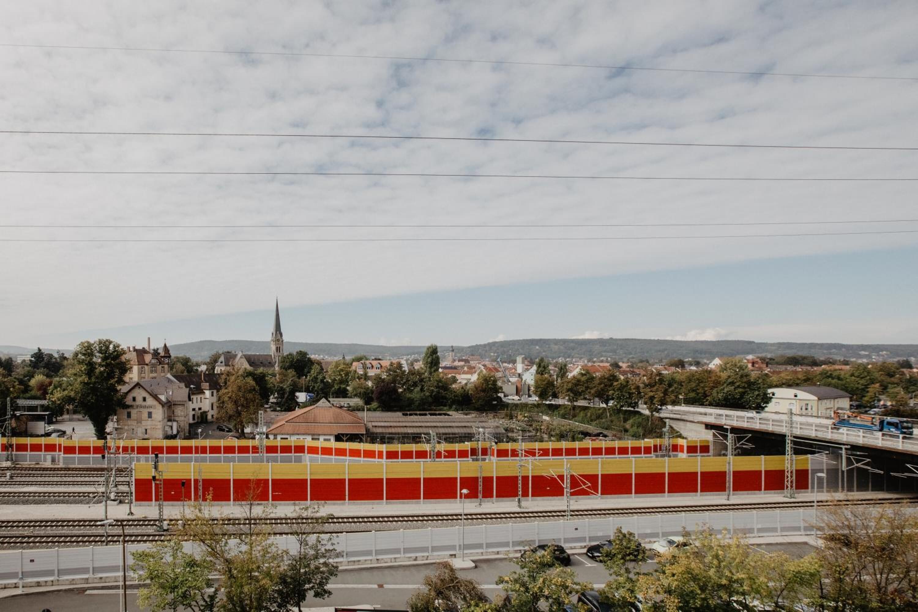 Una stazione ferroviaria con binari, un ponte e edifici circostanti.