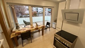 A modern kitchen with a dining area, large windows, and a view of buildings outside. - Privatunterkunft AARON (Magdeburg)