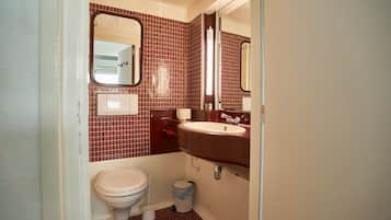 A compact bathroom with a toilet, sink, and mirror.