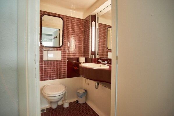 Une petite salle de bain comprenant des toilettes, un lavabo et un miroir.