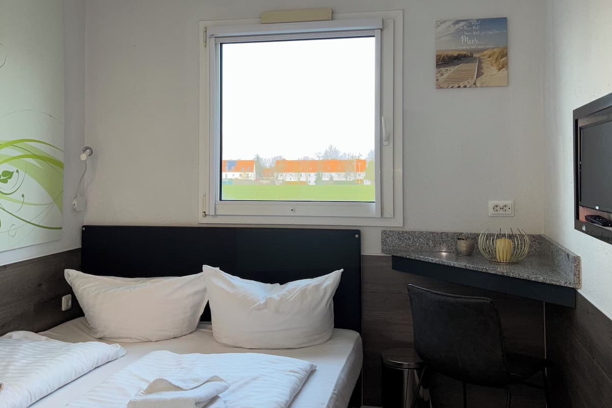 A hotel room with a bed, a desk, a chair, a window with a view, and a television.