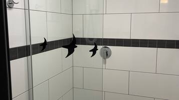 A glass-enclosed shower with white tiles and a black decorative border.