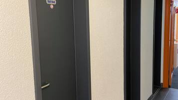 Ein Flur mit schwarzen Türen, einer Überwachungskamera und einem Schild, das einen beschränkten Bereich kennzeichnet.