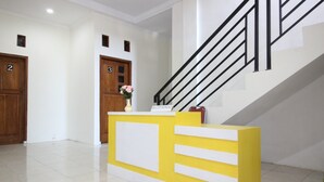 A reception desk with a yellow and white design, a staircase with black railings, and wooden doors numbered 2 and 3. - RedDoorz near UGM 3 (Depok)