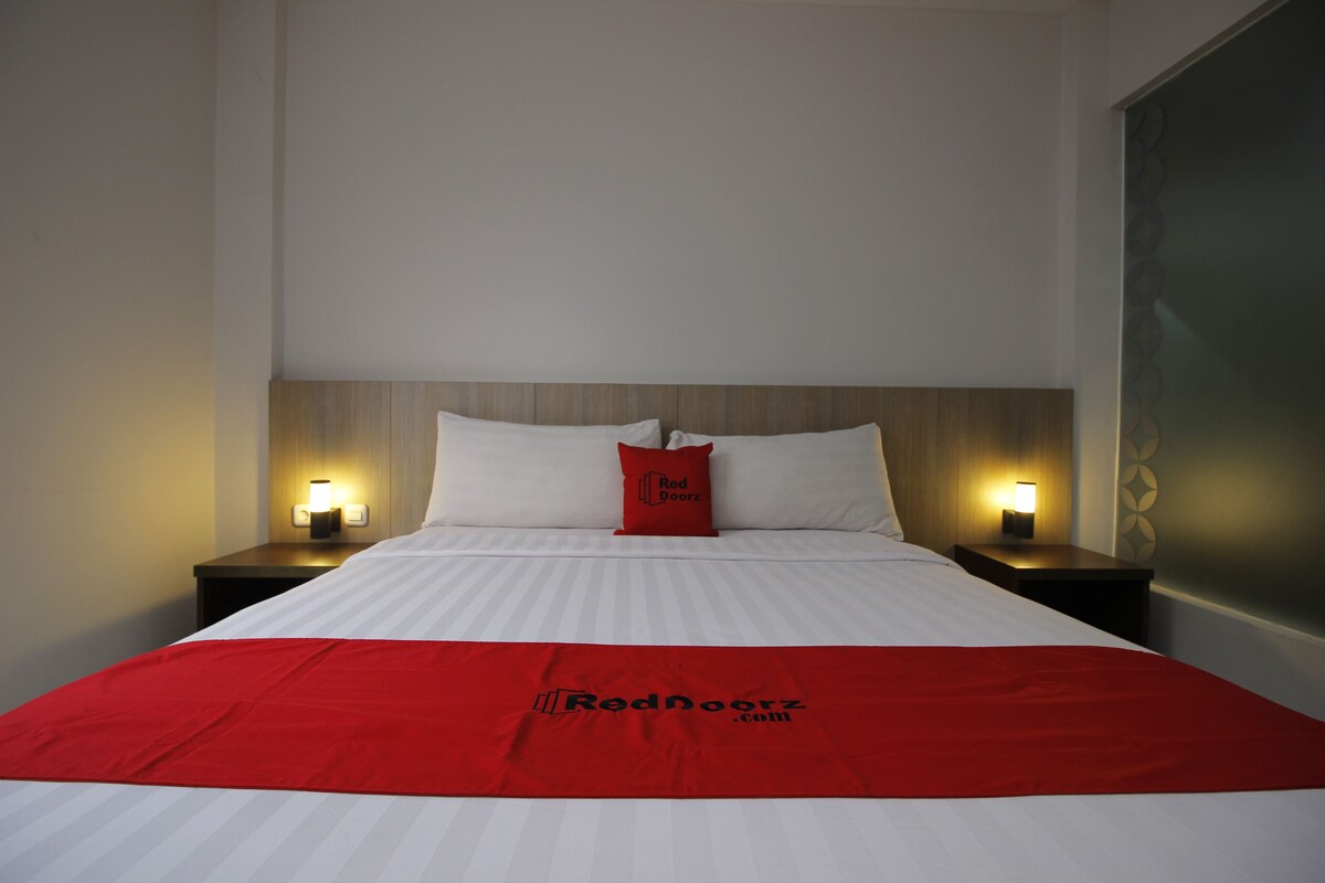 A hotel room with a bed, two bedside tables, and a headboard.