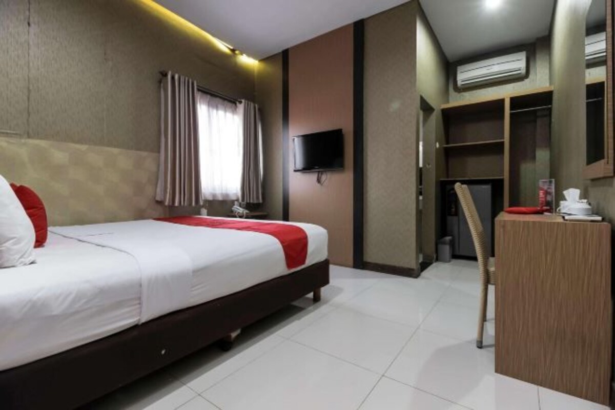 Habitación de hotel con cama, televisión, escritorio y armario.