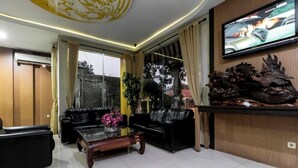 Una sala de estar moderna con sofás de cuero negro, una mesa de centro de madera y un televisor montado en la pared.
