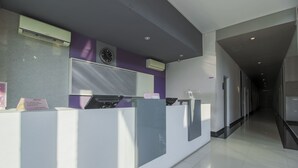 Una zona de recepción con diseño moderno, que incluye un mostrador de recepción, unidades de aire acondicionado y un reloj en la pared.