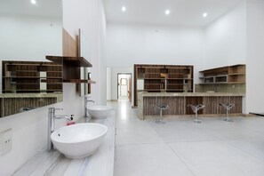 A modern bathroom with a large mirror, two sinks, and wooden shelving. - RedDoorz Premium @ Gandaria Jagakarsa (Jakarta)
