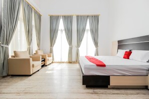 A modern hotel room with a bed, a sofa, and a chair. - RedDoorz Premium @ Gandaria Jagakarsa (Jakarta)
