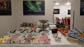 A buffet table with various food items and a painting of the aurora borealis on the wall. - Guesthouse Gerði (Hali)