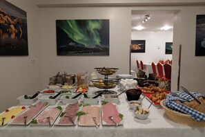 Une table de buffet garnie de divers plats et, au mur, un tableau représentant des aurores boréales.