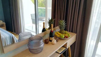Une chambre d’hôtel avec un bureau en bois, une bouteille de champagne, des fruits et un miroir.