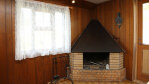 Un intérieur en bois agrémenté d’une cheminée en briques, d’un rideau en dentelle et d’une porte ornée d’une plaque décorative.