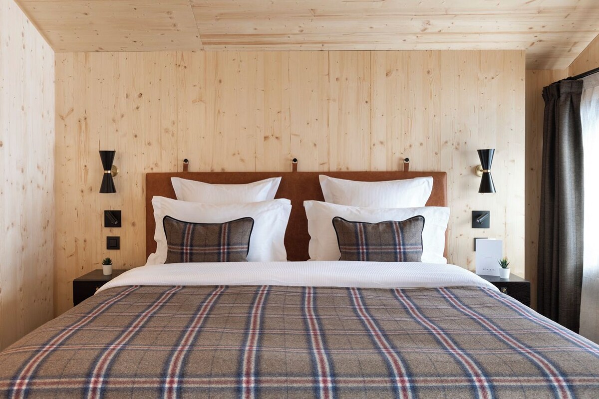 Un dormitorio con paneles de madera, una cama, dos mesitas de noche y lámparas de pared.