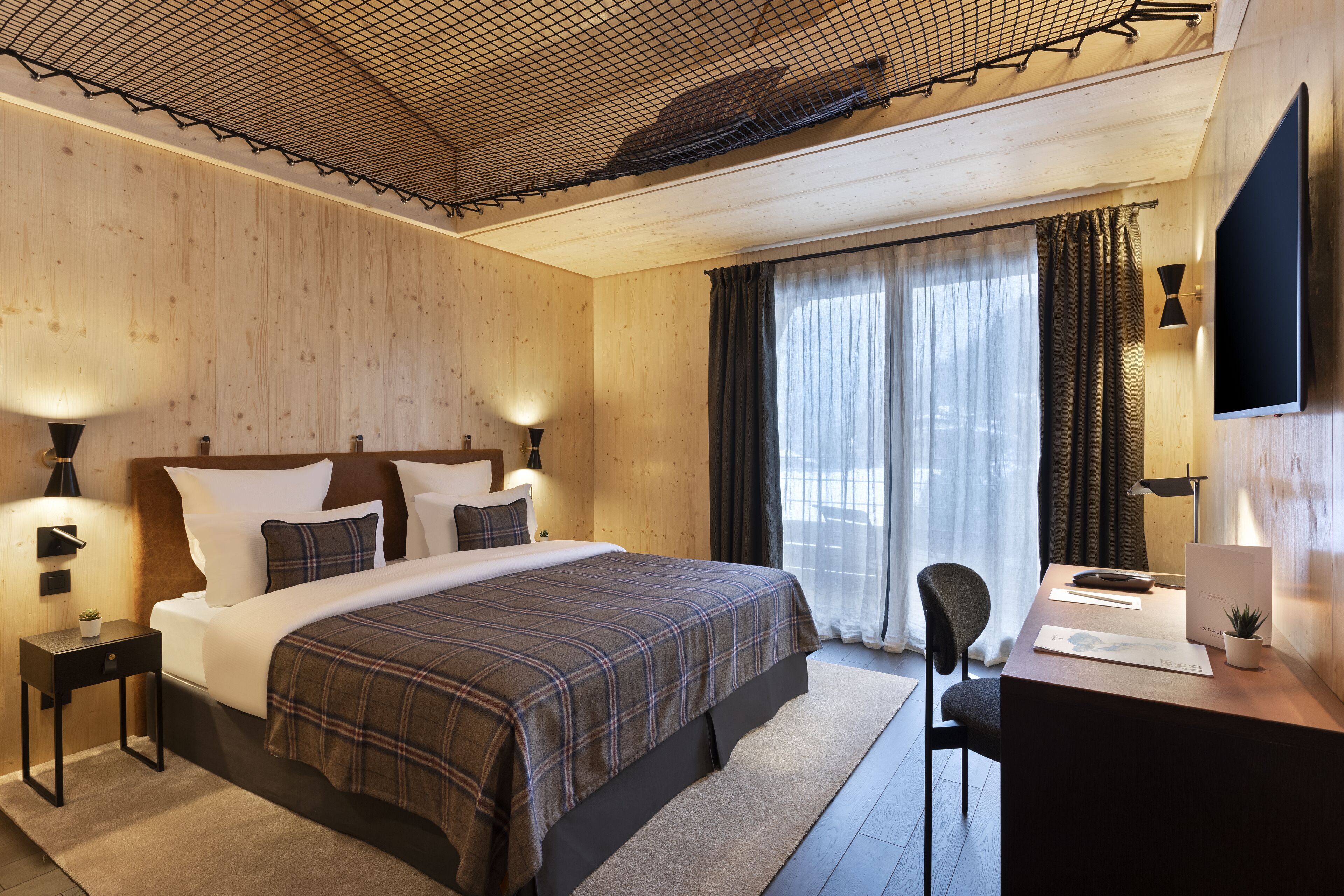 Ein modernes Hotelzimmer mit einem großen Bett, einem Schreibtisch und einem Fernseher.