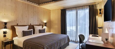 A modern hotel room with a large bed, a desk, and a TV.