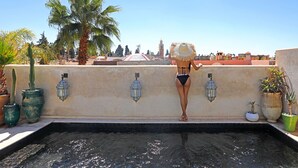 A pool area with a view of palm trees and buildings in the background. - Dar Kandi (Marrakech)