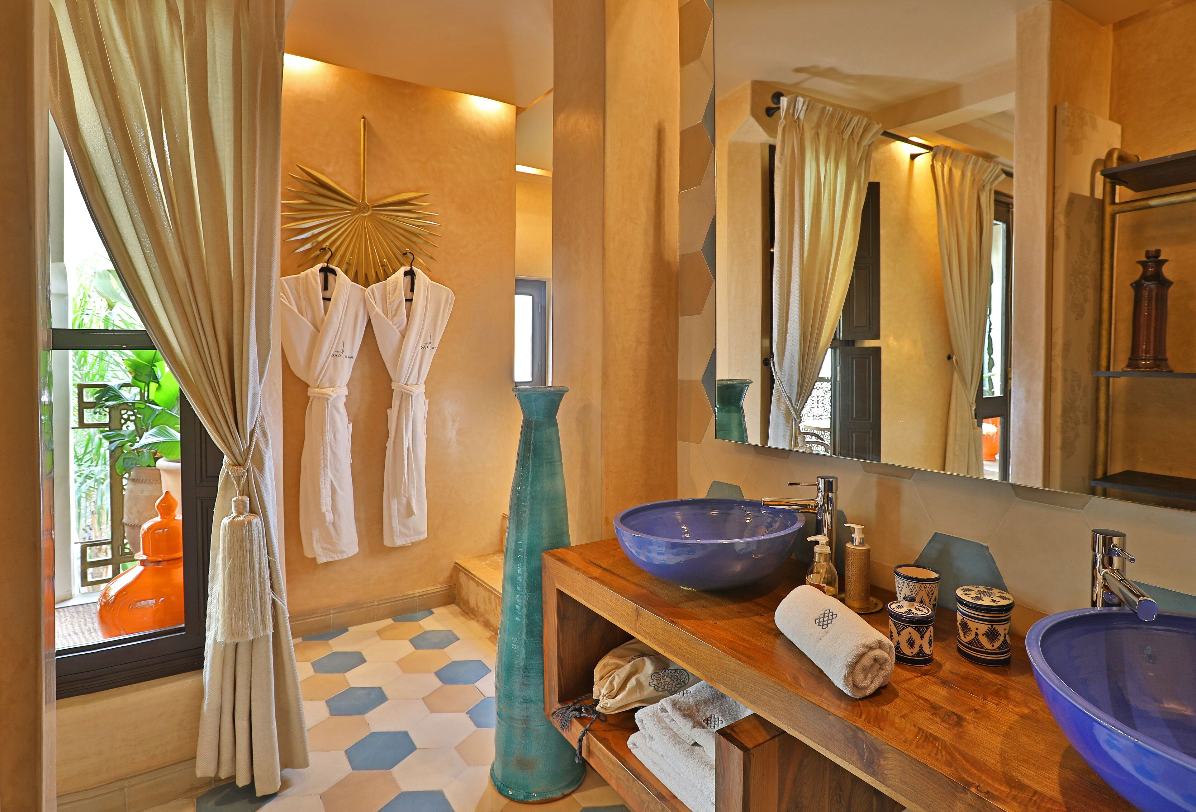 A bathroom with a large mirror, a blue basin, and two towels on a wooden shelf.