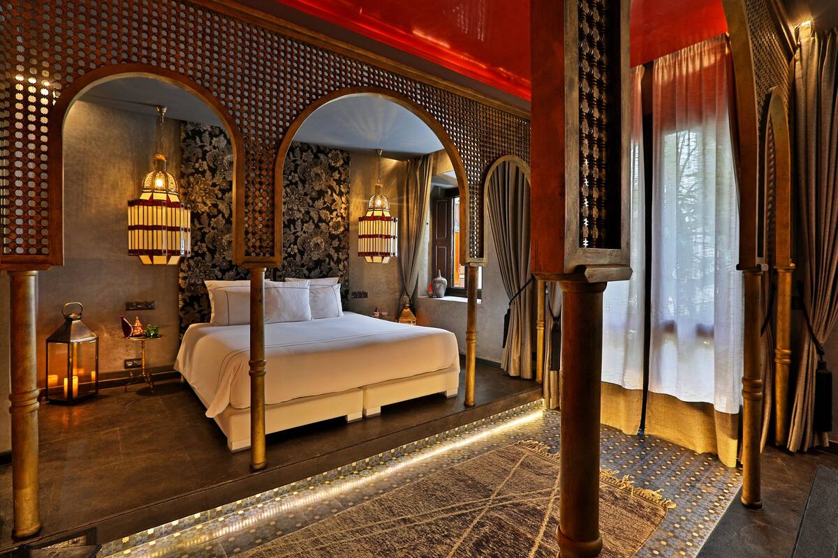 Ein luxuriöses Schlafzimmer mit einem großen Bett, aufwändig gestalteten hölzernen Bögen und dekorativer Beleuchtung.