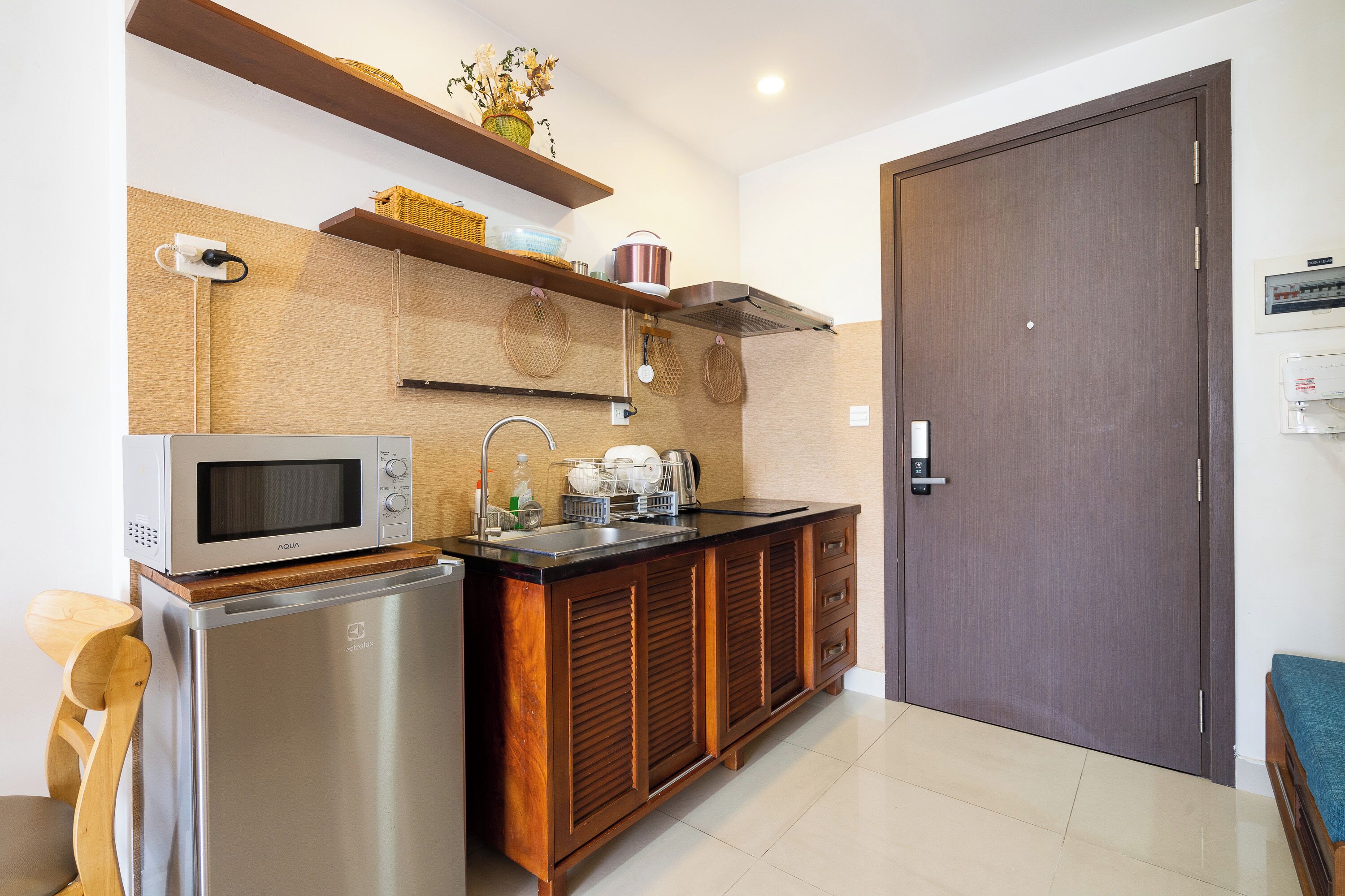 A compact kitchen with a microwave, refrigerator, sink, and wooden cabinets.