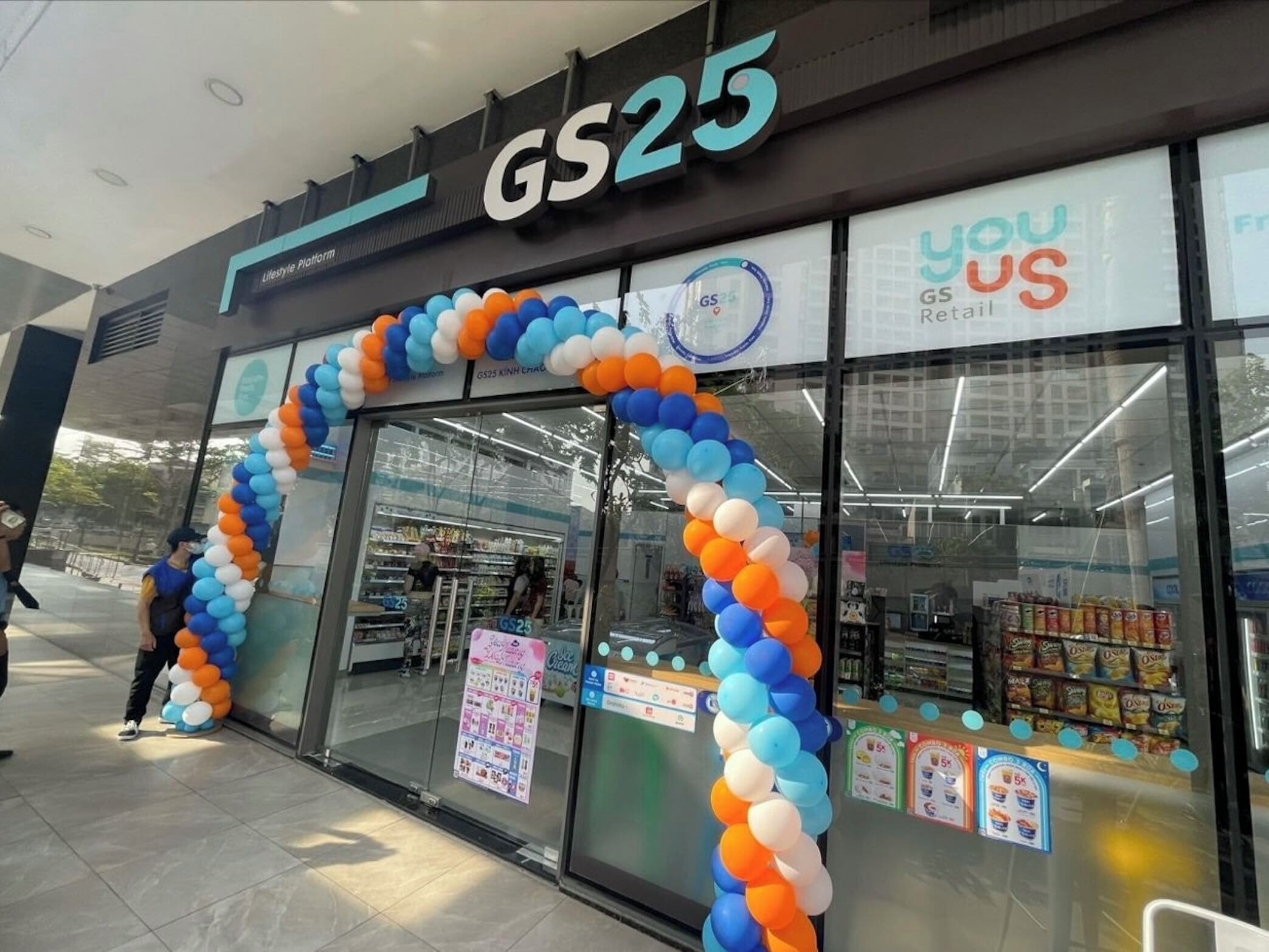 Un magasin GS25 orné d’une grande arche composée de ballons bleus et oranges.