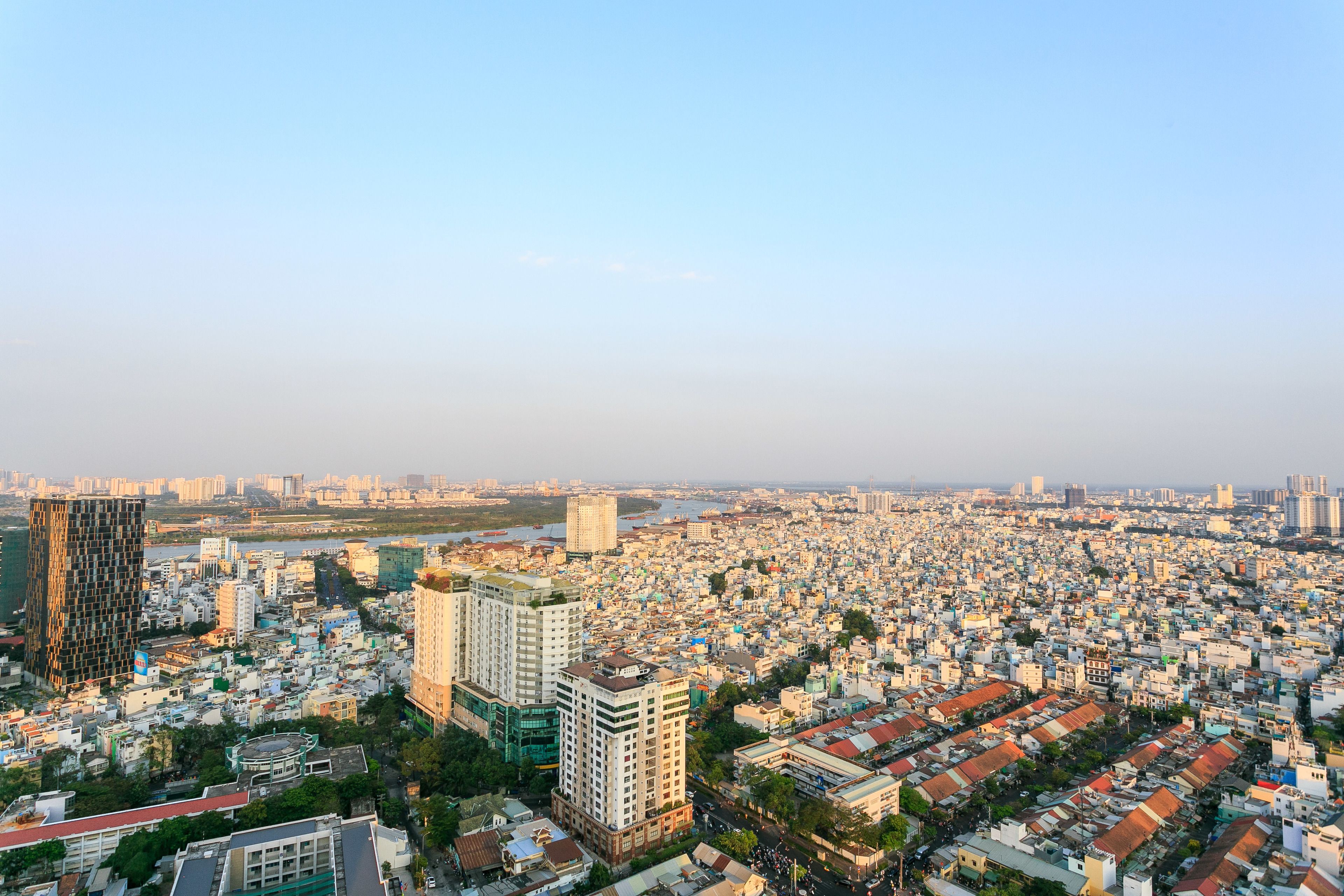 Une vue urbaine avec des bâtiments imposants, une rivière en arrière-plan et un ciel dégagé.