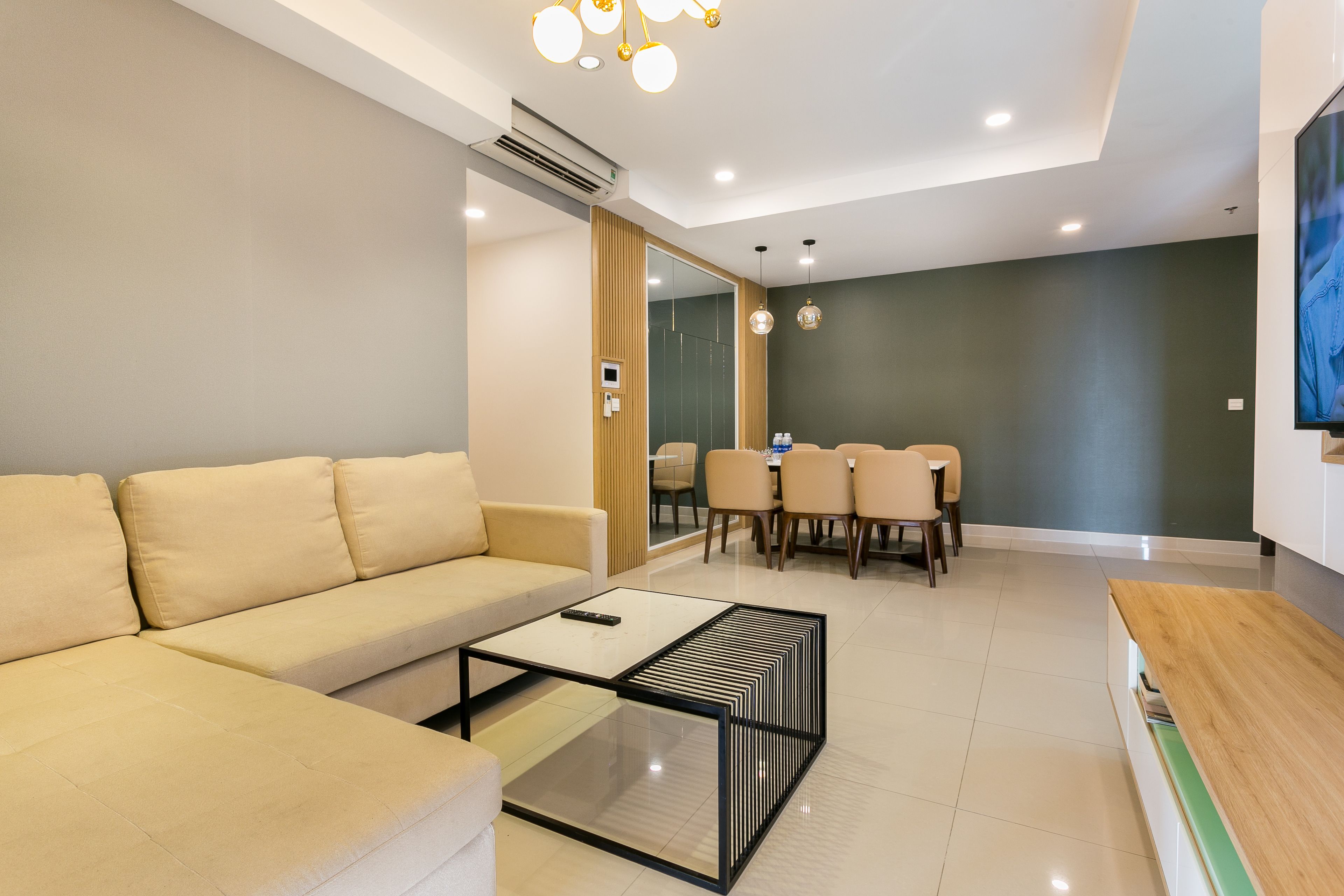A modern living room with a sofa, a coffee table, and a dining area with chairs and a table.