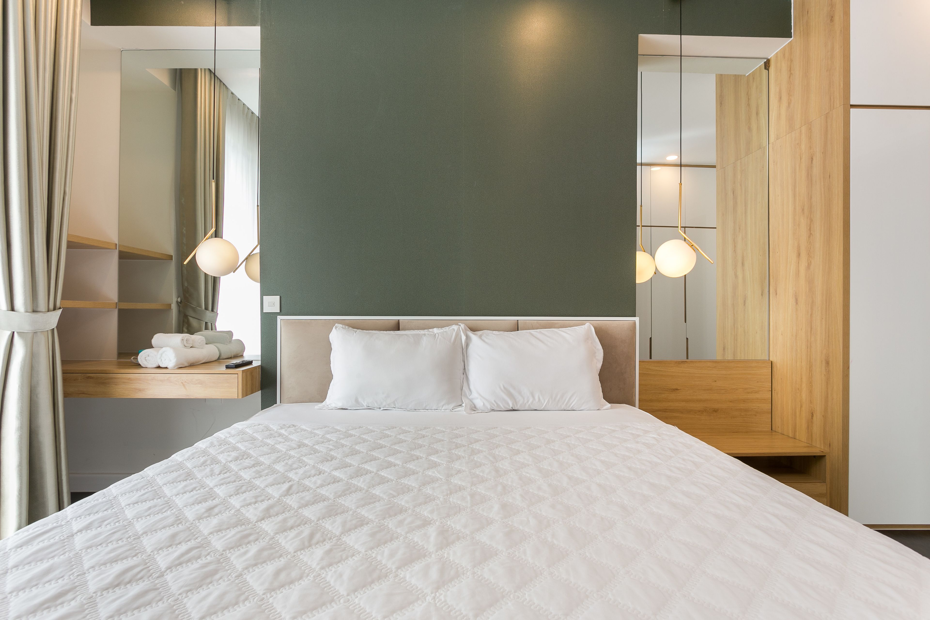 A neatly made bed with a quilted white duvet, a wooden headboard, and two bedside lamps.