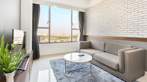 A modern living room with a sofa, a coffee table, a TV, and a large window with curtains. - Saigon Apartment - RiverGate Residence (Ho Chi Minh City)
