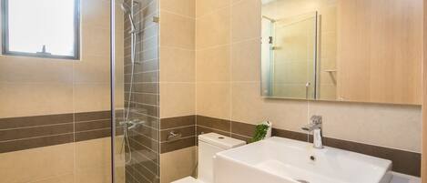 A modern bathroom with a glass shower enclosure, a toilet, and a sink with a mirror above it.