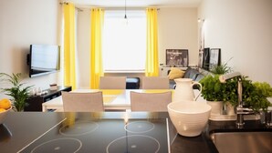 Ein modernes Wohnzimmer mit Esstisch, einer Couch und einem an der Wand befestigten Flachbildfernseher.