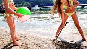 Two individuals on a sandy beach with a lake and forested hills in the background. - Familienhotel Steindl (Millstatt)