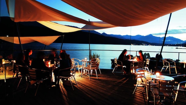An outdoor dining area with tables and chairs, overlooking a body of water and mountains. - Familienhotel Steindl (Millstatt)