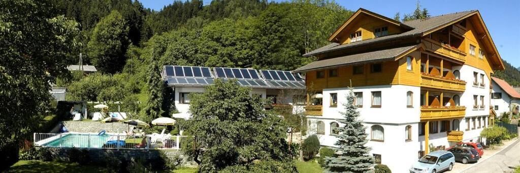 Een hotel met een zwembad, zonnepanelen en een berg op de achtergrond.