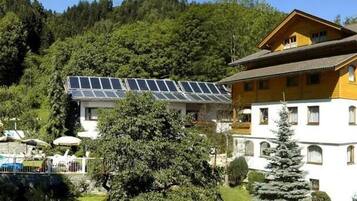 Een hotel met een zwembad, zonnepanelen en een berg op de achtergrond.