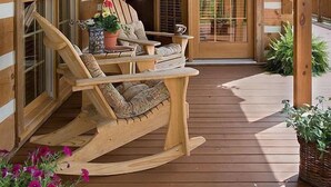 A wooden deck with a rocking chair and a table, a ceiling fan, and a view of the surrounding landscape. - Fish Creek House Bed & Breakfast (Whitehall)